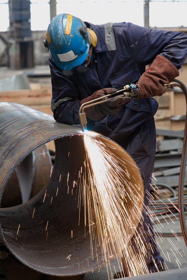 expert cutting a steel pipe with a gas cutter